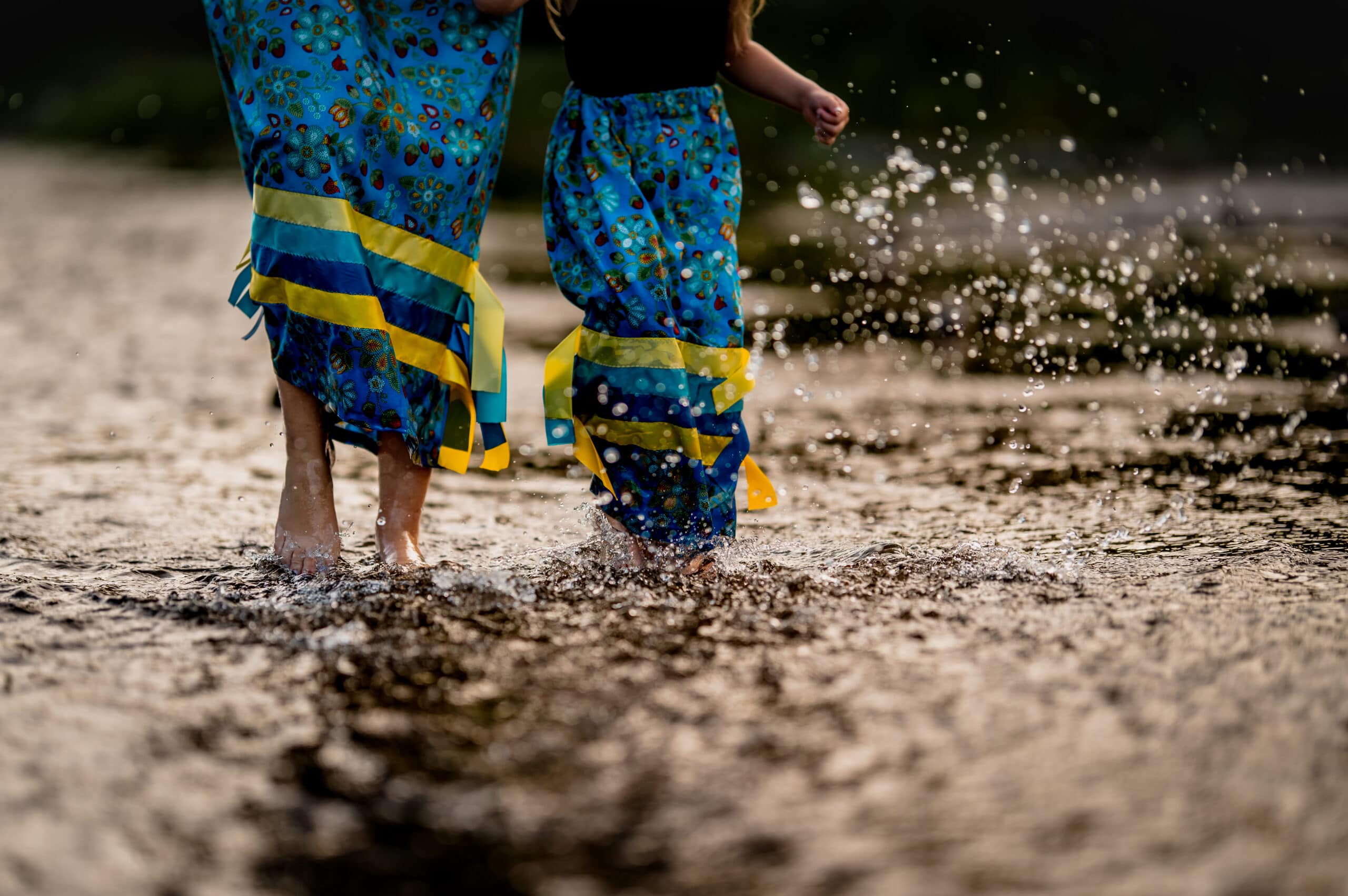 Spirit of the Salmon River_ A woman and girl run through the water in matching blue ribbon skirts