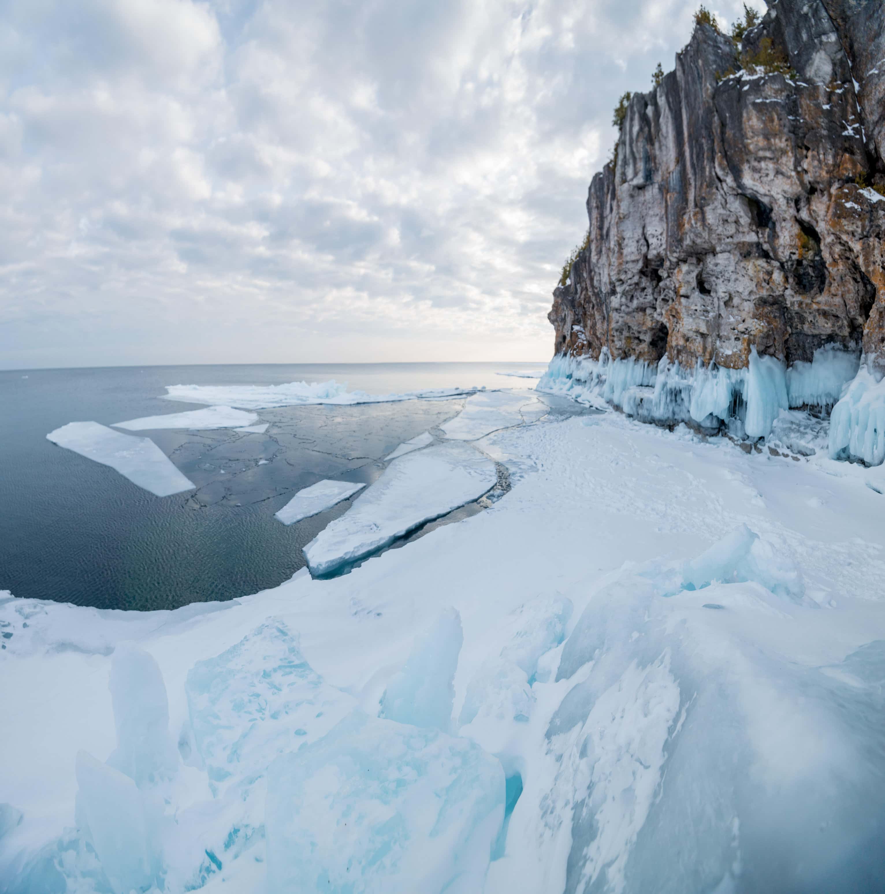 Small chunks of ice break away from the shore and begin floating out to the deeper part of the lake.